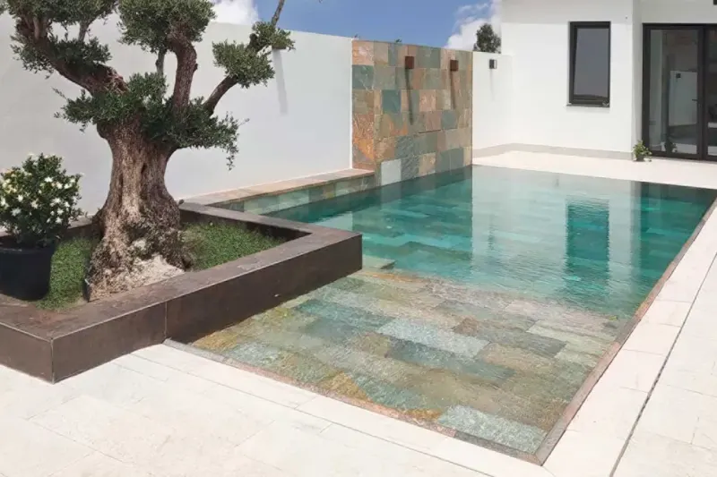 Piscina revestida con gres porcelánico Rosa Gres, con el agua y el borde en continuidad con la terraza