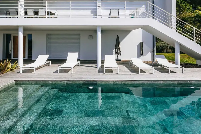 Piscina de skimmers acabada en gres porcelánico, con el coronamiento al mismo nivel que la terraza