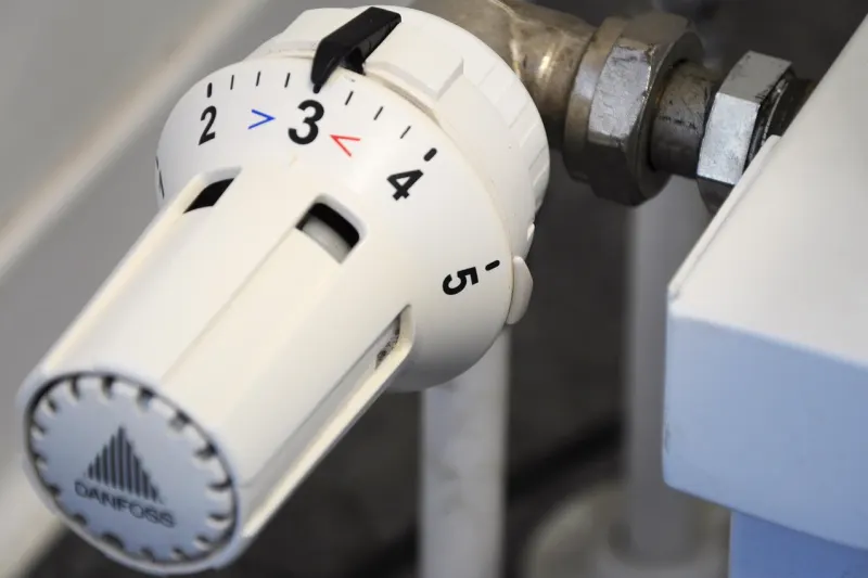 Mano girando la válvula termostática de un radiador